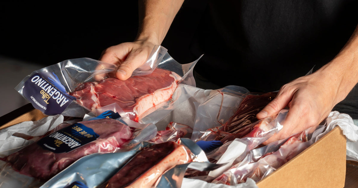 Hands packing vacuum-packed cuts into a delivery box